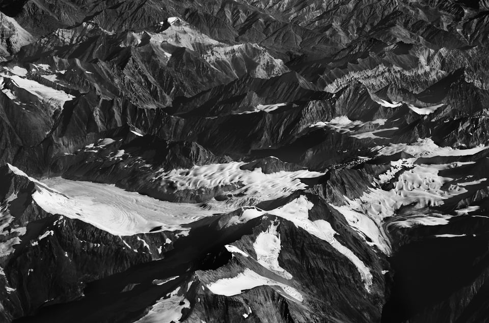 Black and white image of mountains with snow shot from distance