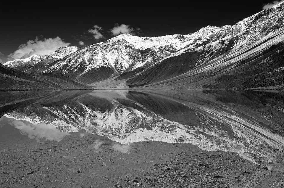 A black and white reflection shot of mountains with snow
