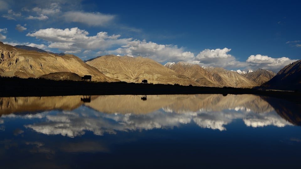 A dark lake reflection with mountains in the background