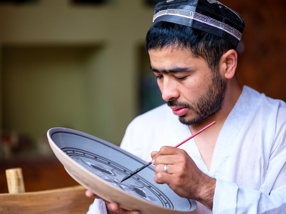 A ceramic apprentice working on a plate