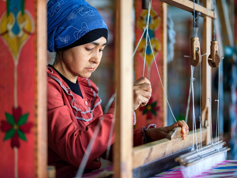 A woman working on a wooden loom in Yodgorlik Silk Factory in Margilan, Uzbekistan