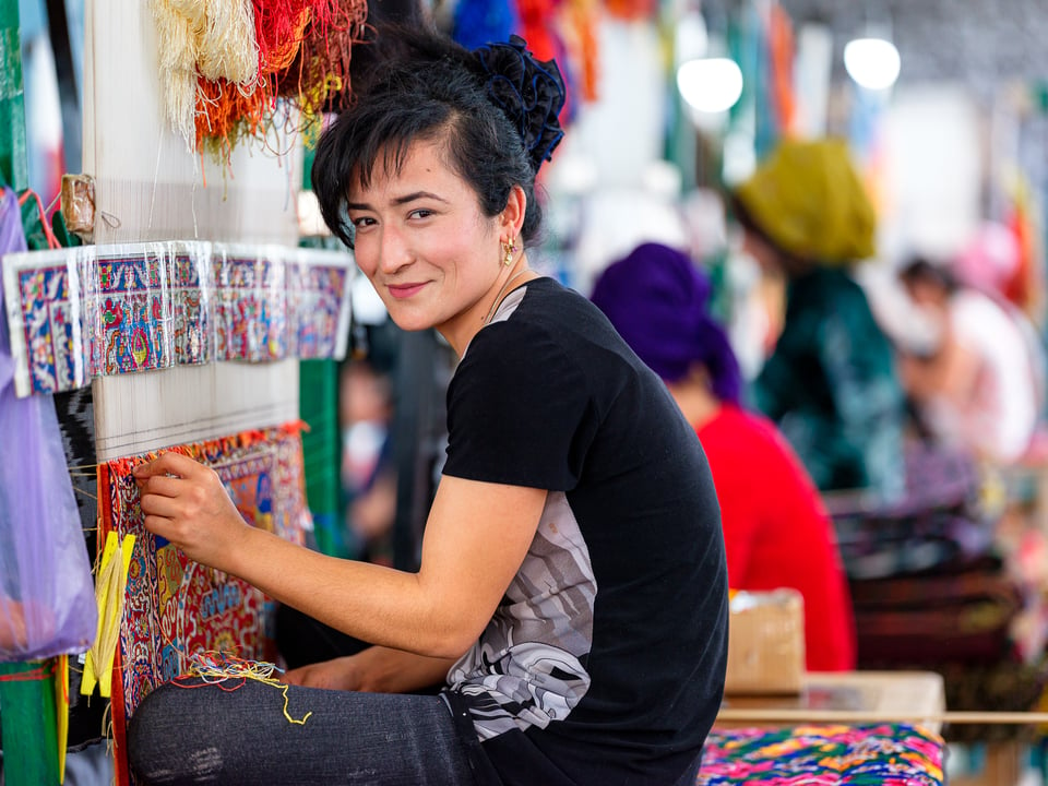 A woman working on a silk carpet