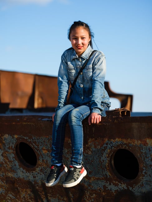 Local girl climbing a ship in the ship graveyard in Muynak