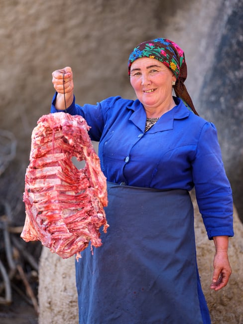 Uzbek woman holding lamb on a skewer, Uzbekistan