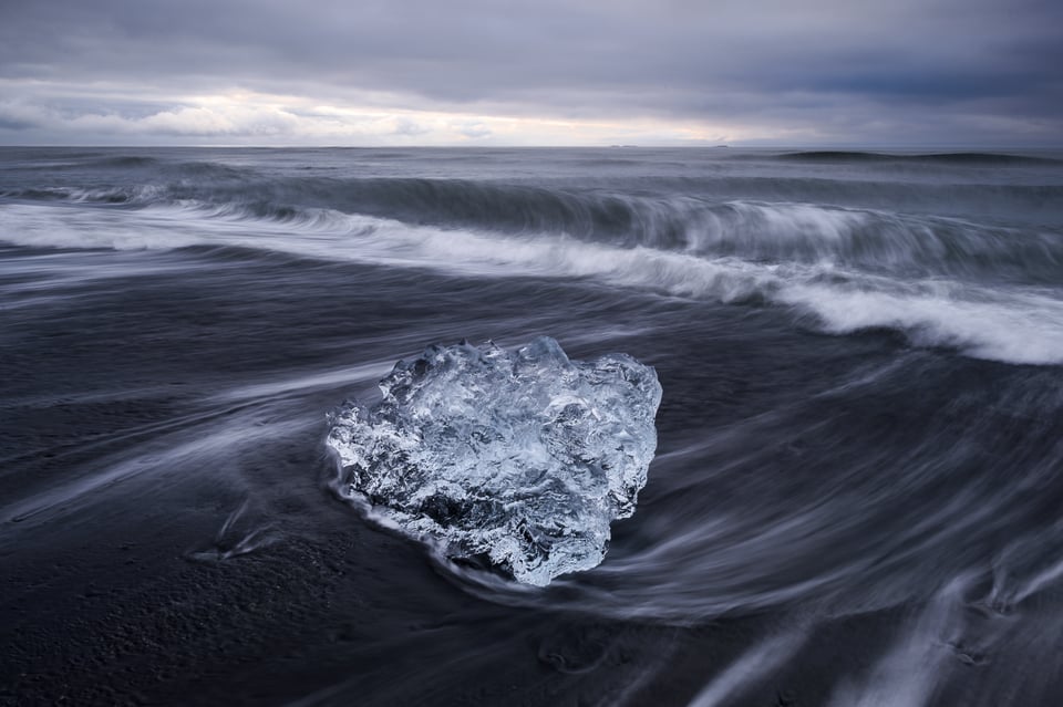 Motion blur in the foreground at Jokulsarlon beach with an iceberg on shore