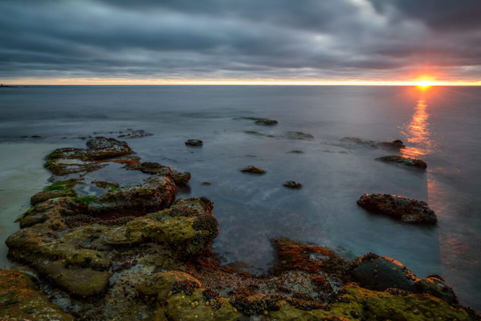 This landscape photo, taken with the Nikon 18-35mm f/3.5-4.5 G lens, shows the sun setting over the ocean.