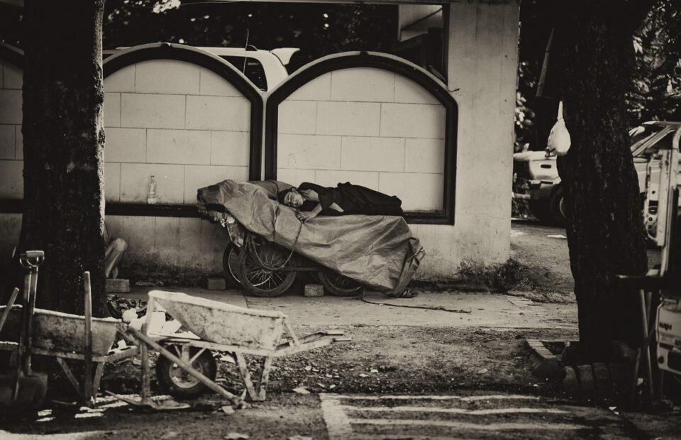 Caption: A young laborer takes a break from the day's work, napping on a cart parked outside the walls of a mansion. The rear end of an SUV parked inside is a barely visible reminder of the stark income inequality that plagues that part of the world.