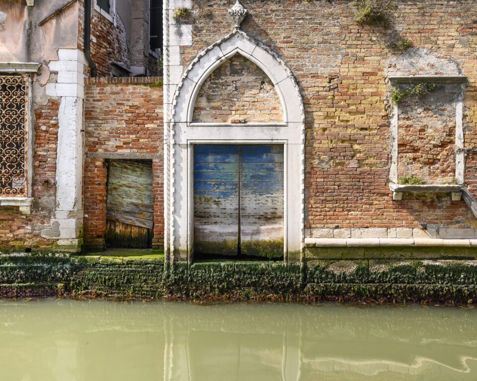 A simple study of beautifully designed and executed architectural detail, set off against ever varied brick work, a visually interesting blue door, much weed and the typical murky green water of a tranquil canal.