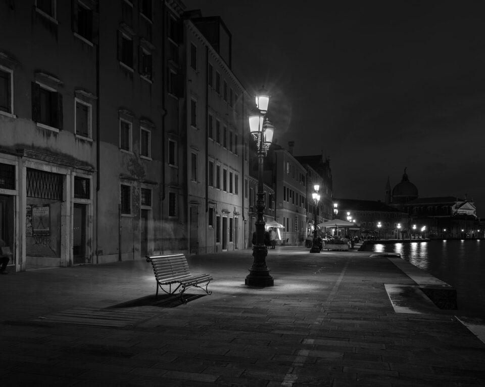 An empty bench and a characteristic 3 light lamppost.